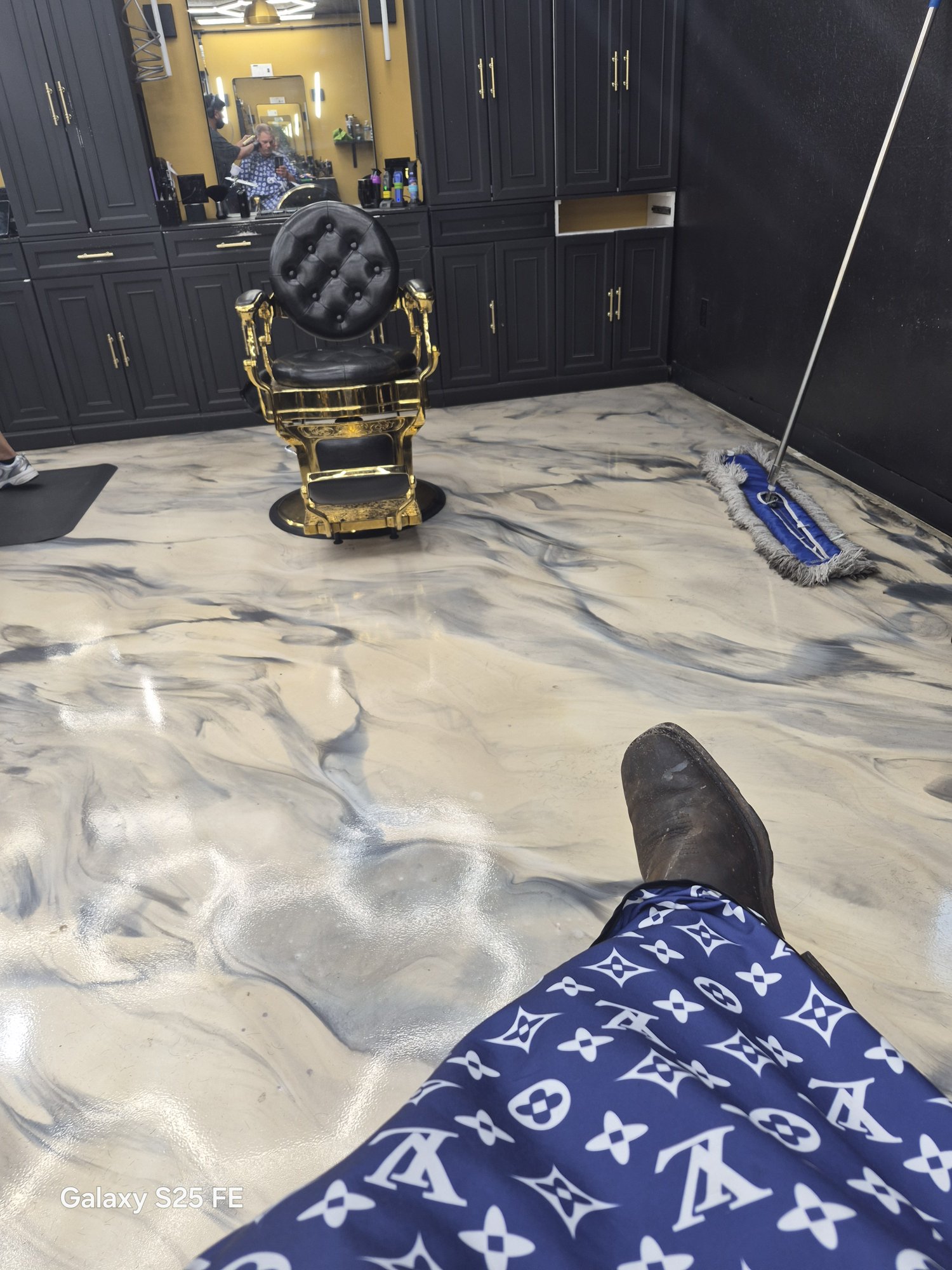 Black and grey marbled metallic floor in a barber shop with gold barber chair