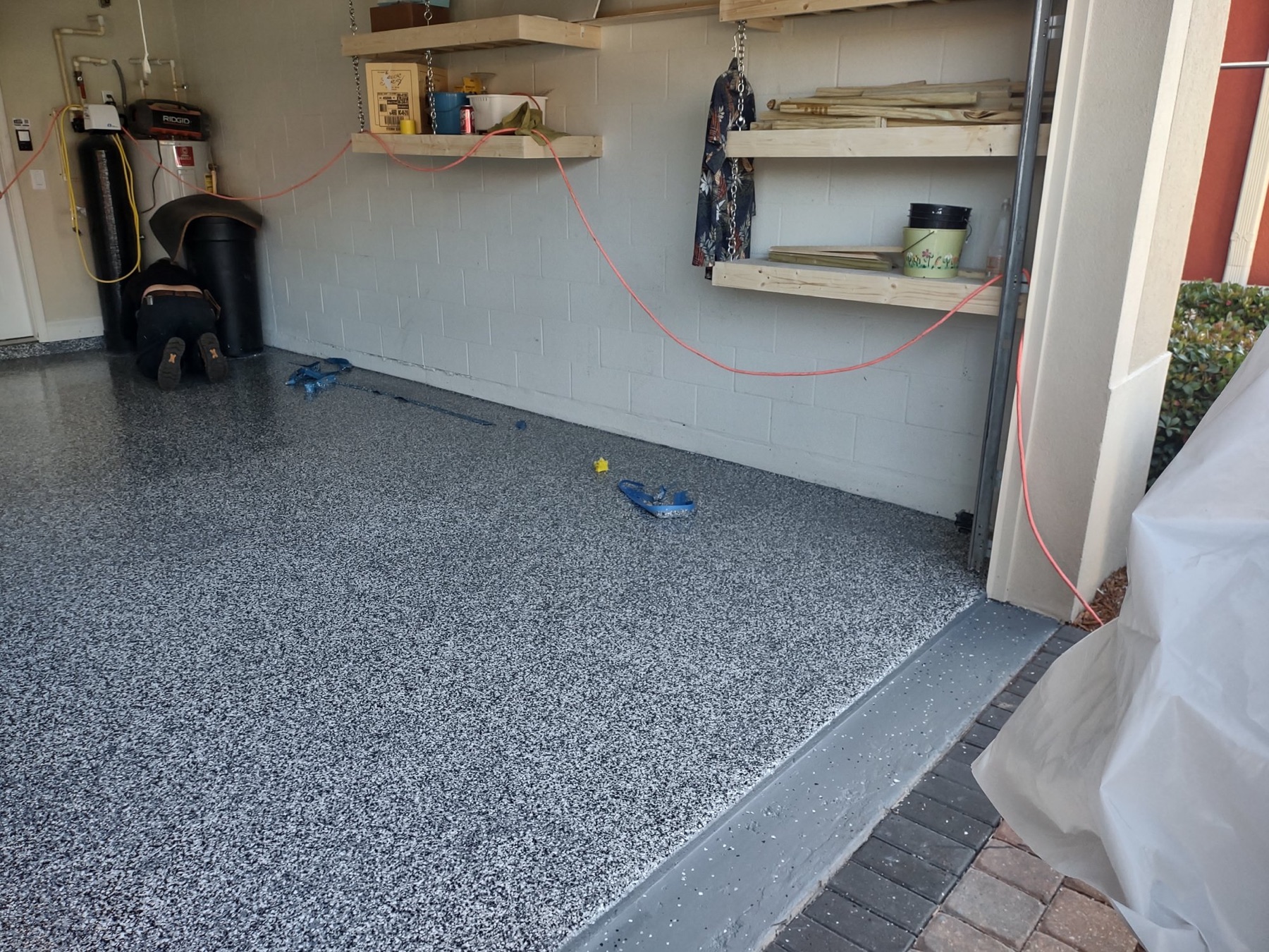 Grey flake garage floor with water heater corner and shelving